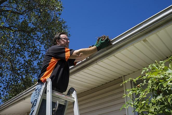 a professional repairman fixing a damaged gutter in Blue Point, NY